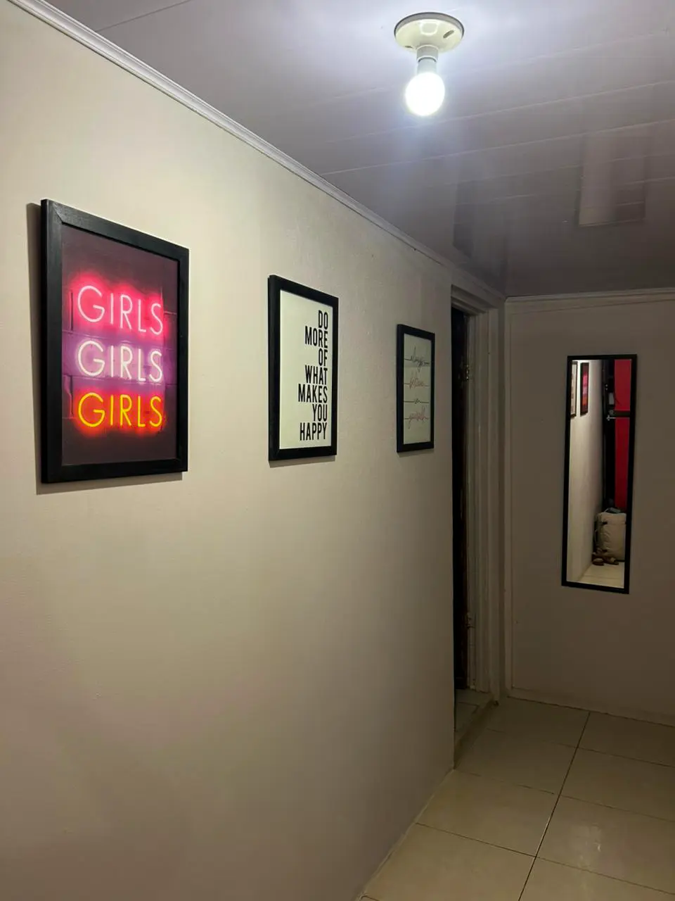 Hostel hallway decorated with 'GIRLS GIRLS GIRLS' neon sign and motivational art.